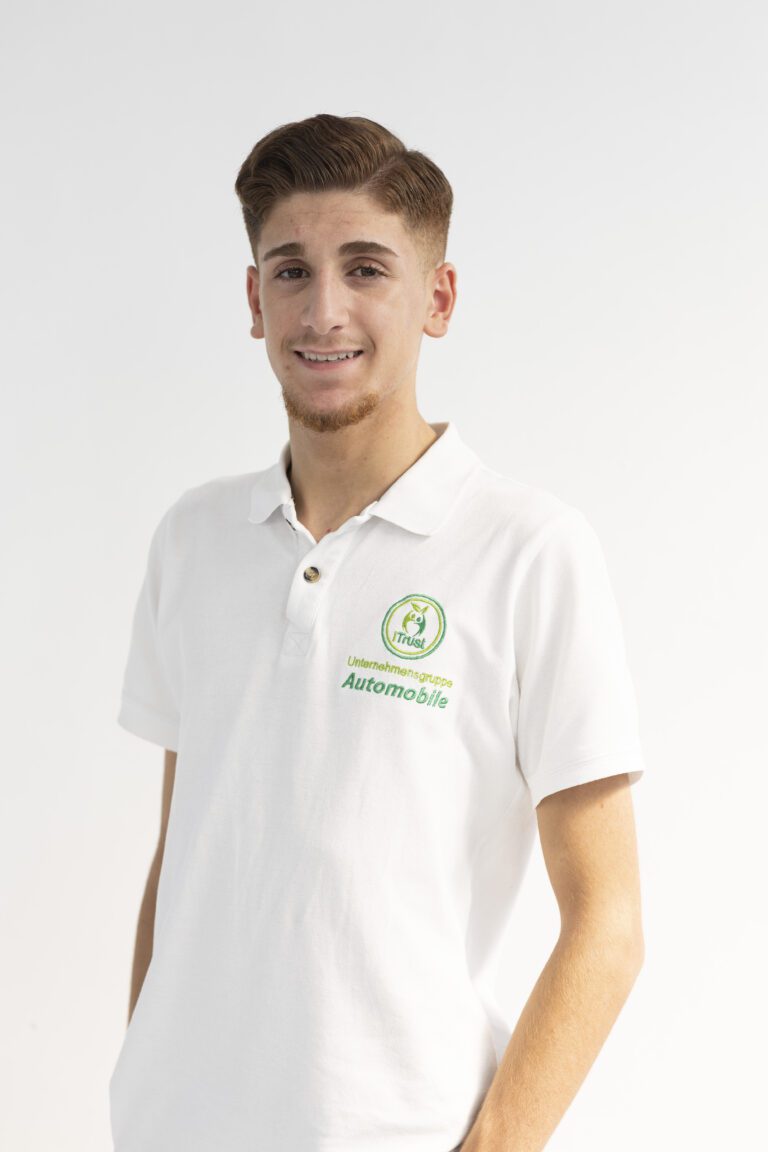 Über uns 4 Über uns: Kerem Tün (Mitarbeiter) posiert für ein Porträtfoto im weißen Poloshirt mit dem Unternehmenslogo.