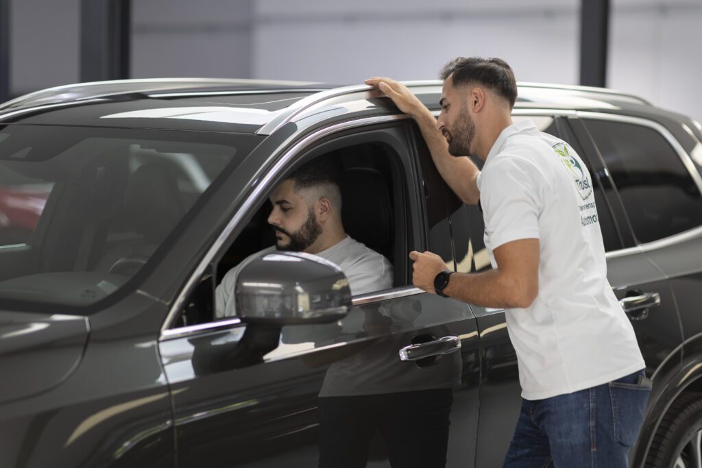 Kunde im Fahrzeug spricht mit einem Autoankauf-Experten bei der Fahrzeugübergabe in Solingen