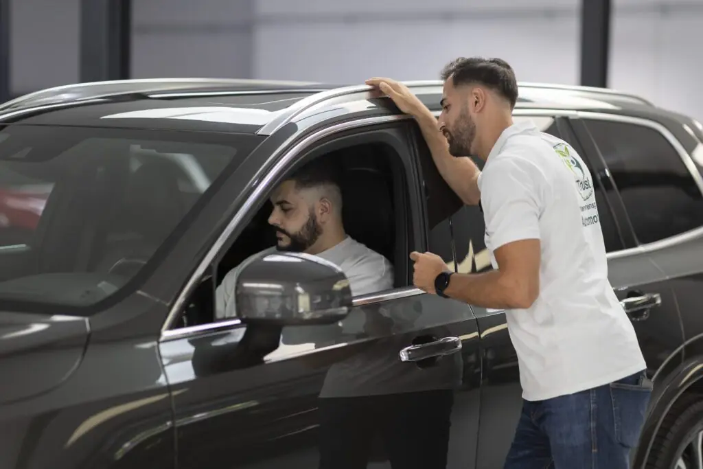 Kunde im Fahrzeug spricht mit einem Autoankauf-Experten bei der Fahrzeugübergabe in Solingen