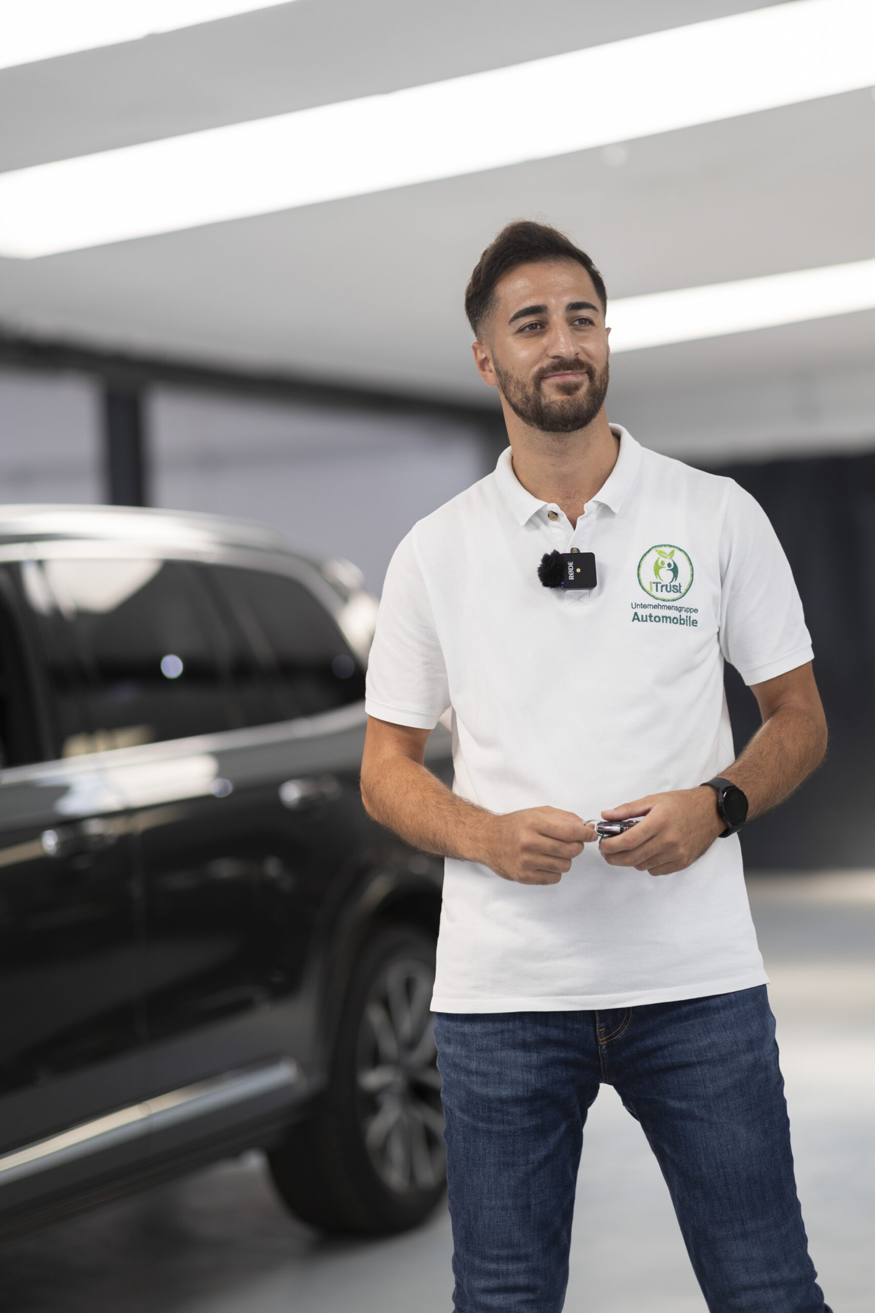Über iTrust Automobile ist Suleyman Tün mit Fahrzeugschlüssel vor einem Gebrauchtwagen im Autohaus in Solingen.