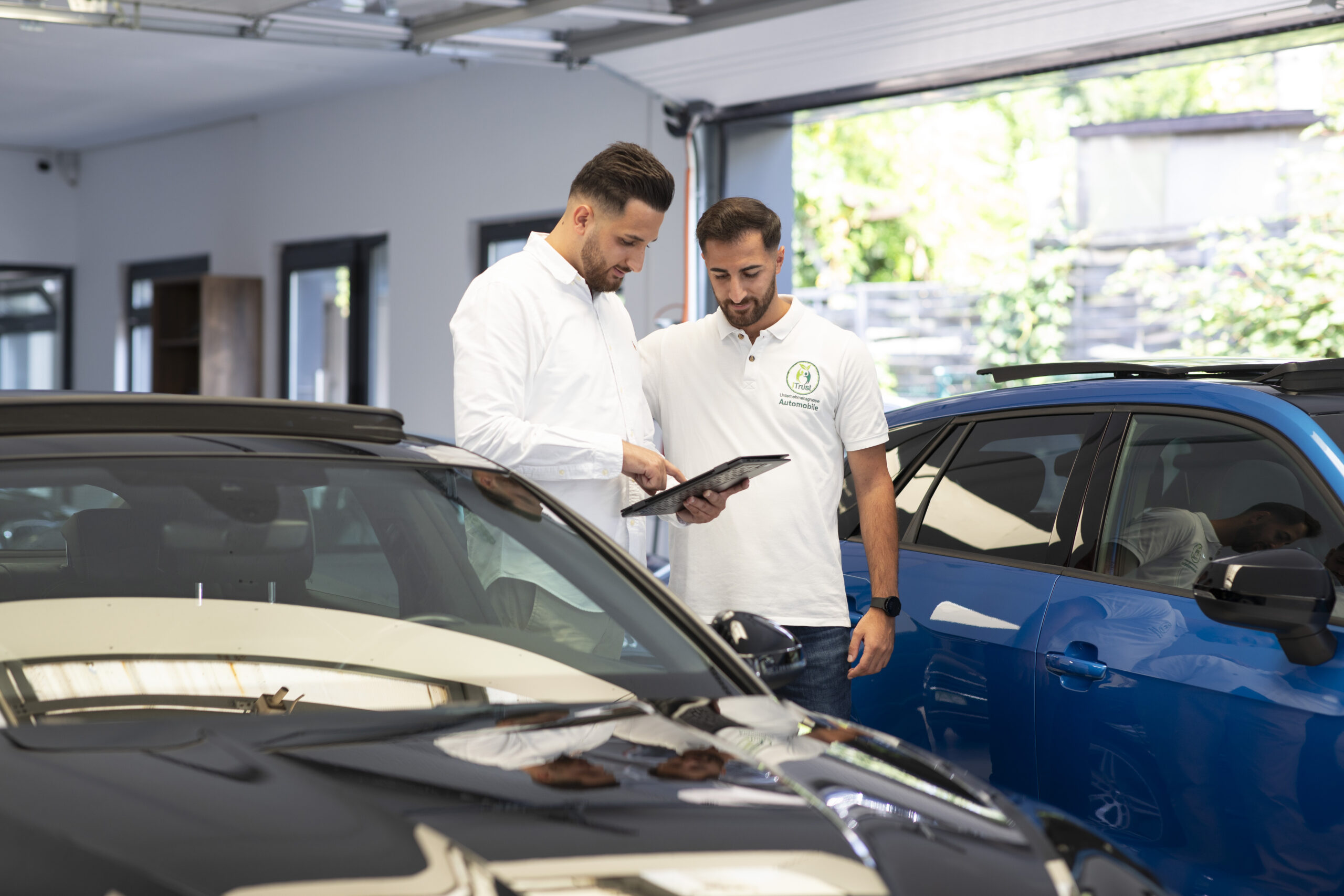 Über iTrust Automobile kontrollieren Sefkan- und Suleyman Tün die Fahrzeugdaten auf einem Tablet im Autohaus in Solingen.