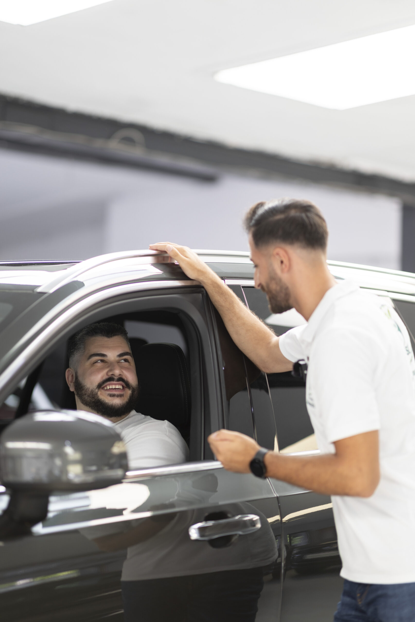 Beim Autohaus Service Solingen berät Suleyman Tün von iTrust Automobile einen Kunden persönlich in einem Fahrzeug.